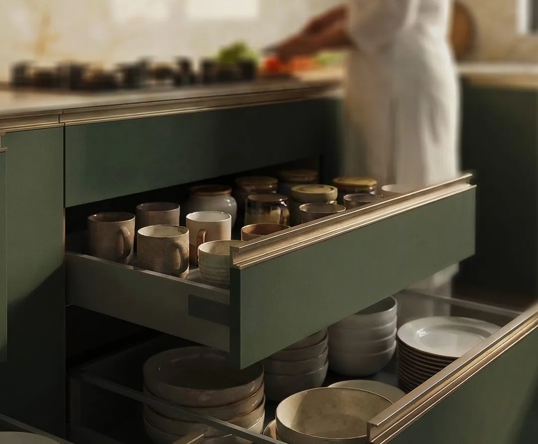 Deep green kitchen drawers with brass trims holding crockery