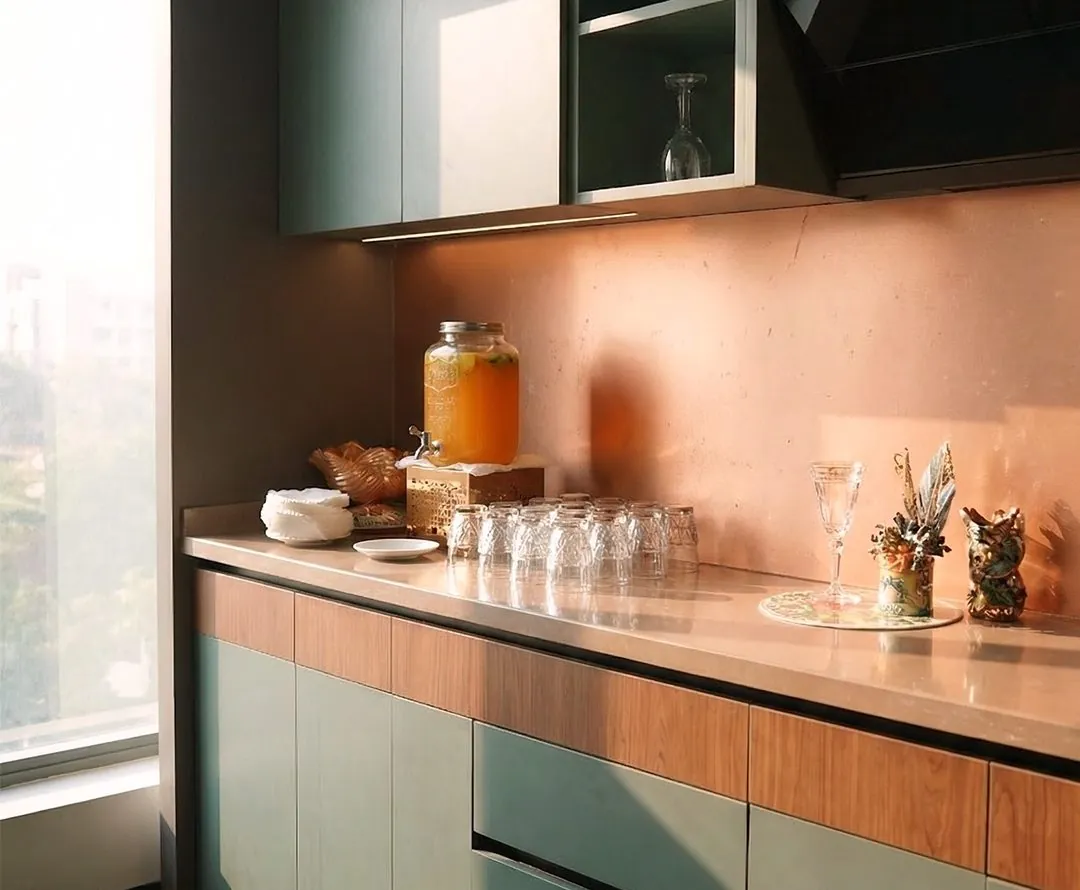 Sage green kitchen with walnut drawer fronts and copper-toned backsplash